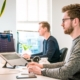 man sitting on chair wearing gray crew neck long sleeved shirt using Apple Magic Keyboard