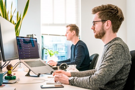 man sitting on chair wearing gray crew neck long sleeved shirt using Apple Magic Keyboard